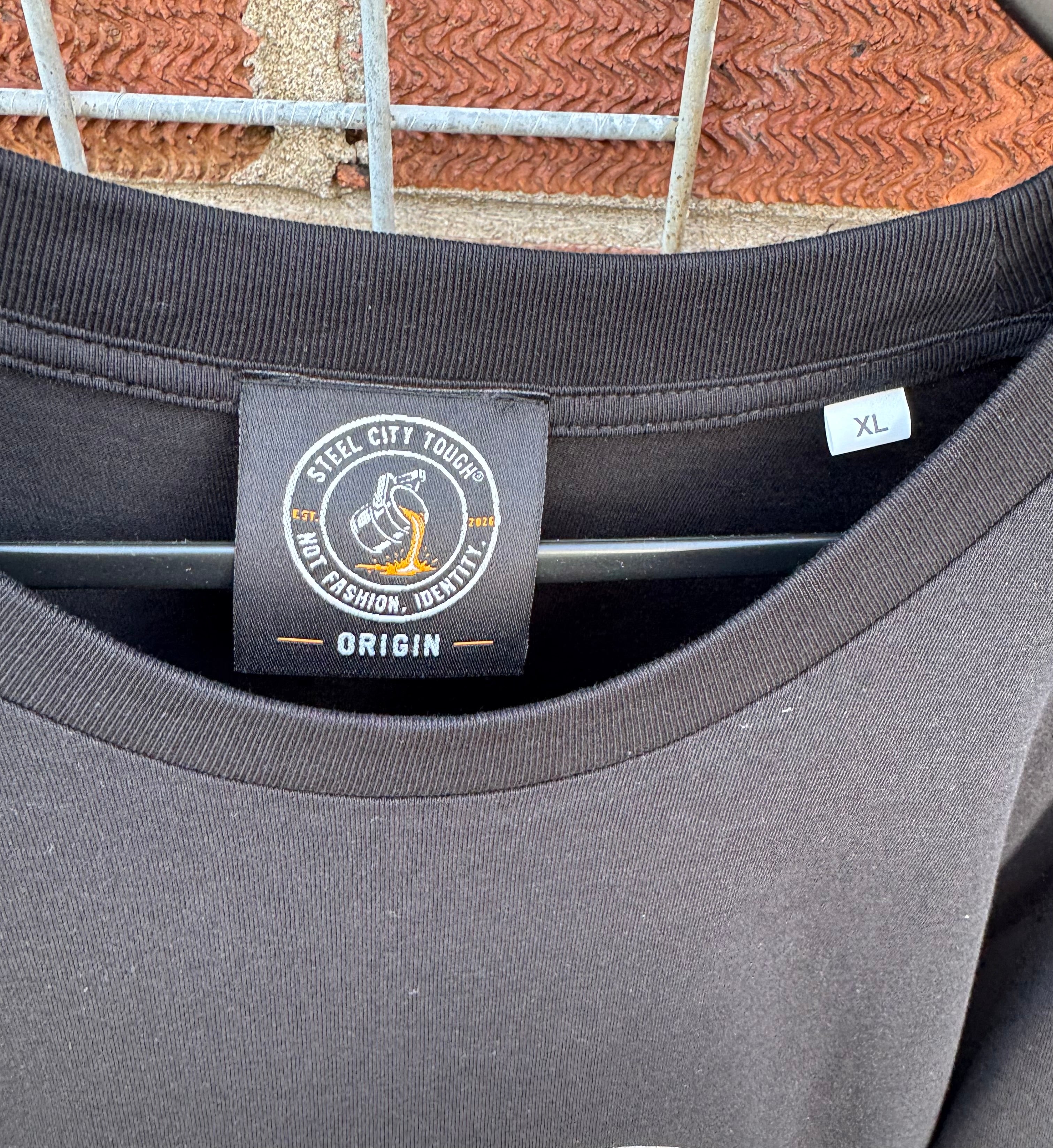 close up of woven neck label and reinforced rib collar of Steel city Tough Origin T-shirt